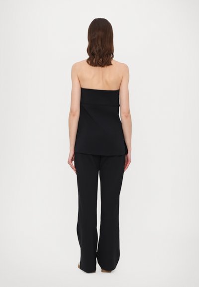 Svart strapless topp med jevn tekstur og skreddersydd passform, kombinert med svarte vide bukser. Antrekket har et rent, minimalistisk design.