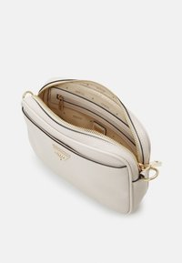 Creme læder crossbody taske med guld hardware, dobbelt lynlåslommer og indvendigt logo mønster design. Glat tekstur med en struktureret form.