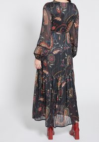 Maksimekko mustalla kukkakuviolla, jossa on pitkät, puffatut hihat. Sisältää kerroksellisen hameen ja eloisia paisley-kuoseja punaisissa, vihreissä ja keltaisissa sävyissä.