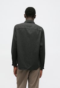 Chemise à manches longues en tissu gris foncé avec une finition texturée, dotée d'un col et de poignets boutonnés, vue de l'arrière.