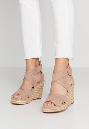 Beżowe sandały na koturnie z zamszu z krzyżującymi się paskami przy kostce i okrągłą klamrą, z plecioną platformą z juty i teksturowaną tkaniną.