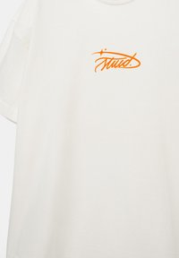 Hvid T-shirt med korte ærmer med lille orange stiliseret tekst "Stud." og to stjernelignende glimt over øverste venstre bryst.