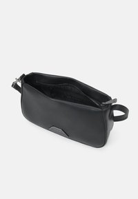 Czarna kosmetyczka ze skóry o gładkiej fakturze, zamykana na zamek błyskawiczny, z bocznym uchwytem. Na przedniej stronie znajduje się akcent z logo.