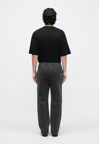 Camisa negra de manga corta y pantalones gris oscuro con cintura ajustable, con un bolsillo trasero, tela suave y un ajuste relajado.
