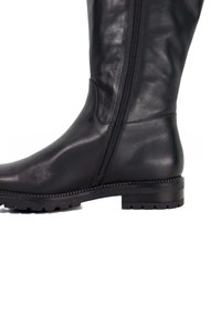 Black leather knee-high boot with textured finish, side zipper, and rugged outsole. Features a stacked heel and rounded toe.