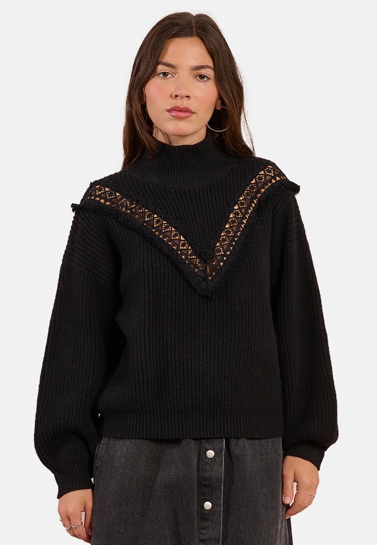 Maglione nero a maglia con colletto alto, caratterizzato da un bordo in pizzo a forma di V e dettagli frangiati lungo la scollatura. Maniche ampie e texture a costine.