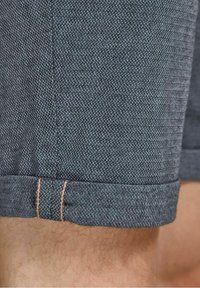 Shorts a quadri blu scuro in tessuto strutturato, con orlo arrotolato e dettagli di cucitura marrone chiaro.