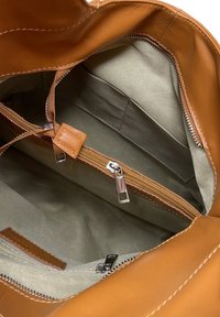 Borsa a mano in pelle color cuoio con un ampio interno, dotata di una fodera in tessuto verde, una tasca con zip e accessori coordinati.