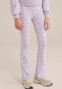 Lila utsvängda leggings med ett vitt blommönster, tillverkade av ett mjukt tyg. Sömlös design sträcker sig från midjan till anklarna.