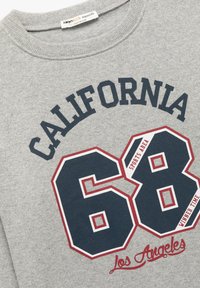 Szara bluza z okrągłym dekoltem. Na przodzie znajduje się napis "CALIFORNIA" w ciemnoniebieskim kolorze, duże, obrysowane cyfry "68" oraz czerwone akcenty.