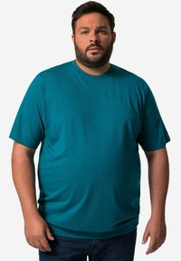 Tyrkysové tričko s krátkým rukávem vyrobené z bavlněné směsice, s kulatým výstřihem a malým logem na levé hrudi. Hladká textura, volný střih.