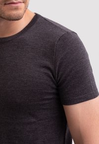Tmavě šedé tričko s krátkým rukávem vyrobené z měkké, texturované tkaniny, s klasickým kulatým výstřihem a přiléhavým střihem.