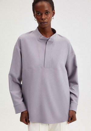 Lavendelkleurige blouse met lange mouwen en opstaande kraag, met subtiele naaddetails en een relaxte pasvorm, gemaakt van zachte, gestructureerde stof.