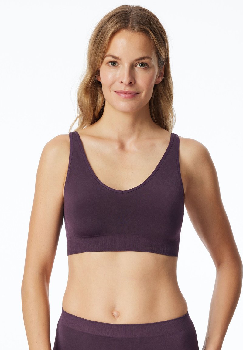 Soutien-gorge violet sans coutures avec une encolure profonde et des bretelles larges. Fabriqué en tissu doux et extensible pour le confort. Texture lisse, sans matériel visible.