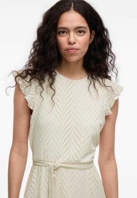 Helles Kleid mit einem strukturierten Muster aus kleinen Löchern, mit Rüschensäumen und einem gebundenen Taillendetail, aus weichem Stoff gefertigt.