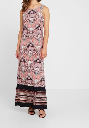 Ärmelloses Maxikleid mit rosa, schwarzen und weißen, detaillierten Paisley- und geometrischen Mustern, kombiniert mit schwarzen Riemchensandalen.