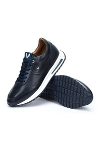 Marineblaue Ledersneaker mit weißer Sohle, runder Zehenform, strukturiertem Gummilaufsohle und dunkelblauen Schnürsenkeln. Mit dezenten Logo-Details akzentuiert.