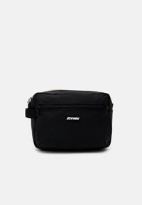 Black nylon crossbody bag with a rectangular shape, featuring a front zip pocket and a logo patch. Simple strap for carrying.