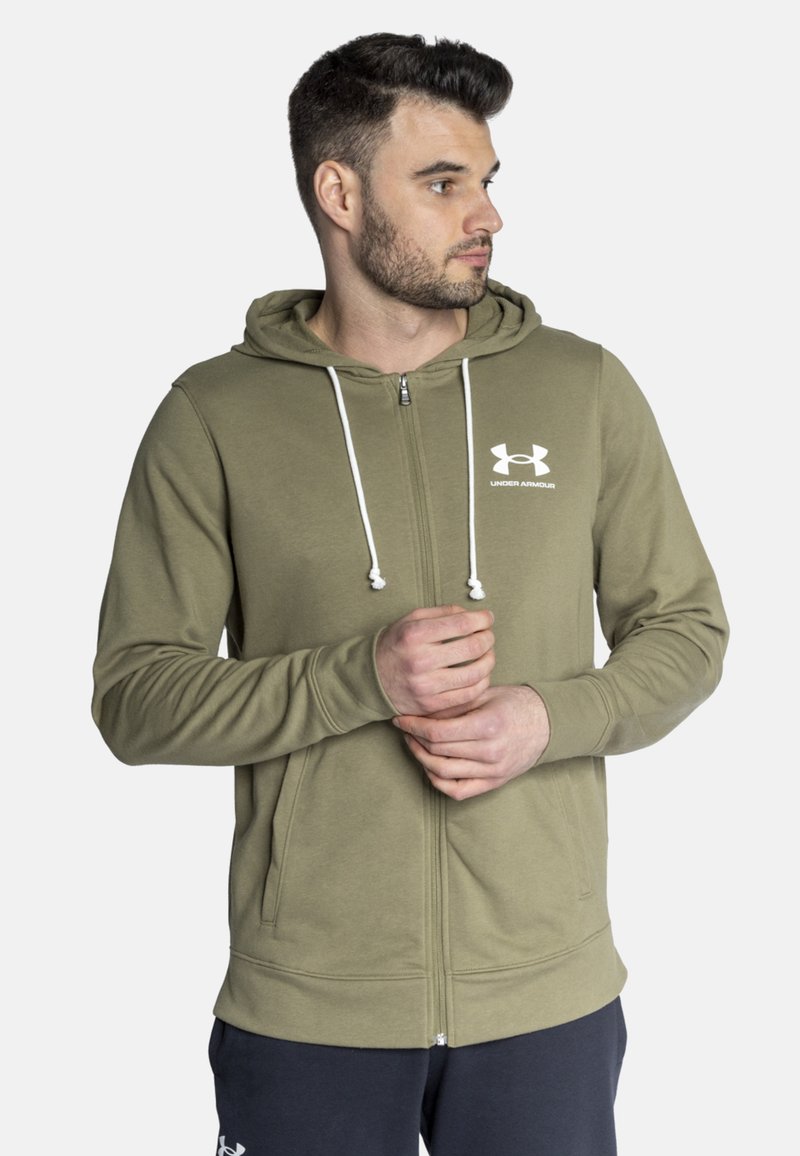 Oliwkowy rozpinany hoodie z przednią kieszenią, białymi sznurkami i białym logo Under Armour na klatce piersiowej. Miękka, teksturowana tkanina.