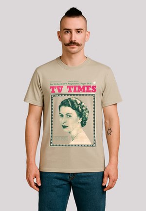 Man with mustache wearing beige T-shirt with vintage "TV TIMES" cover featuring a black-and-white portrait of a woman with curled hair.