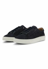 Mörkblå mockaskor med en vit gummisula, som har en minimalistisk design och texturerad yta. Snörning med subtila detaljer.