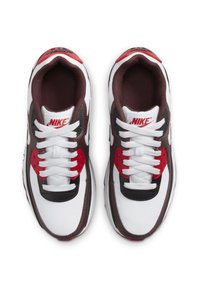 Nike tenisice sa bijelim kožnim gornjim dijelom, crvenim i tamnosmeškim akcentima, okruglim prstom i ravnim pertlama uz podstavljen ovratnik za udobnost.