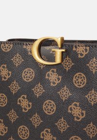 Nærbillede af en brun lædertaske med beige geometriske mønstre og detalje i guldmetal med "G"-lås.