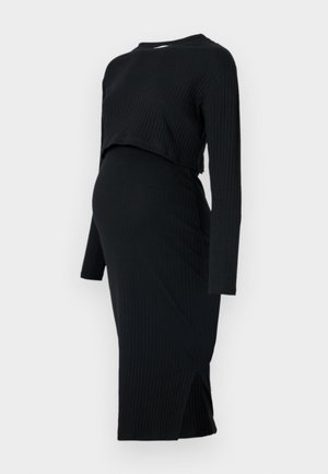 Rochie de maternitate neagră, cu model canalat, cu mâneci lungi și un design scurt, având o siluetă ajustată și o fanta pe latura tivului.