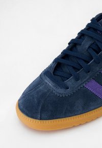 Tengeréskék velúr sneaker lila csíkkal, textúrált felső résszel és bordázott peremű gumi talppal, a kényelem és a tapadás érdekében tervezve.