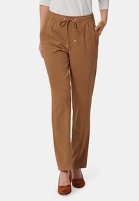 Bruine stretch stofbroek met een elastische tailleband en een trekkoord; heeft zijzakken en een rechte pijp.