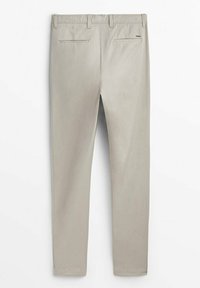 Pantalon beige slim fit avec passants de ceinture et deux poches arrière passepoilées sur fond blanc uni.
