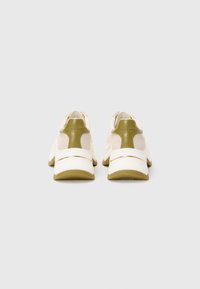 Une paire de baskets beige et vert olive montrée de l'arrière sur un fond blanc uni.