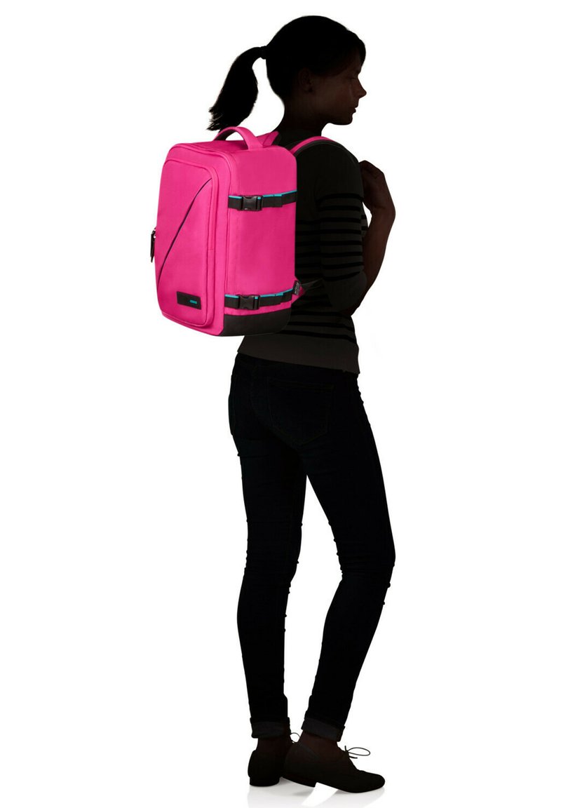 Mochila de tela rosa con detalles negros, múltiples compartimentos, dos correas ajustables y un asa en la parte superior. Textura suave con un mínimo de herrajes.