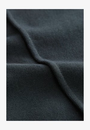 Tamno sivi pleteni materijal s mekom teksturom, sa suptilnim varijacijama i glatkom površinom, nježno savijen kako bi prikazao dubinu i dimenziju.