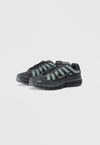Black and mint green athletic shoes with a textured upper, mesh panels, and rubber sole. Features a lacing system and logo accents.