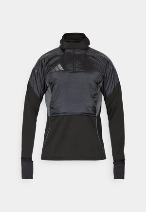 Crna atletska pulover s visokim ovratnikom, prednjim polu-zip zatvaranjem i kontrastnim sjajnim materijalom na ramenima. Ima dugačke rukave i prilagođene manžete.