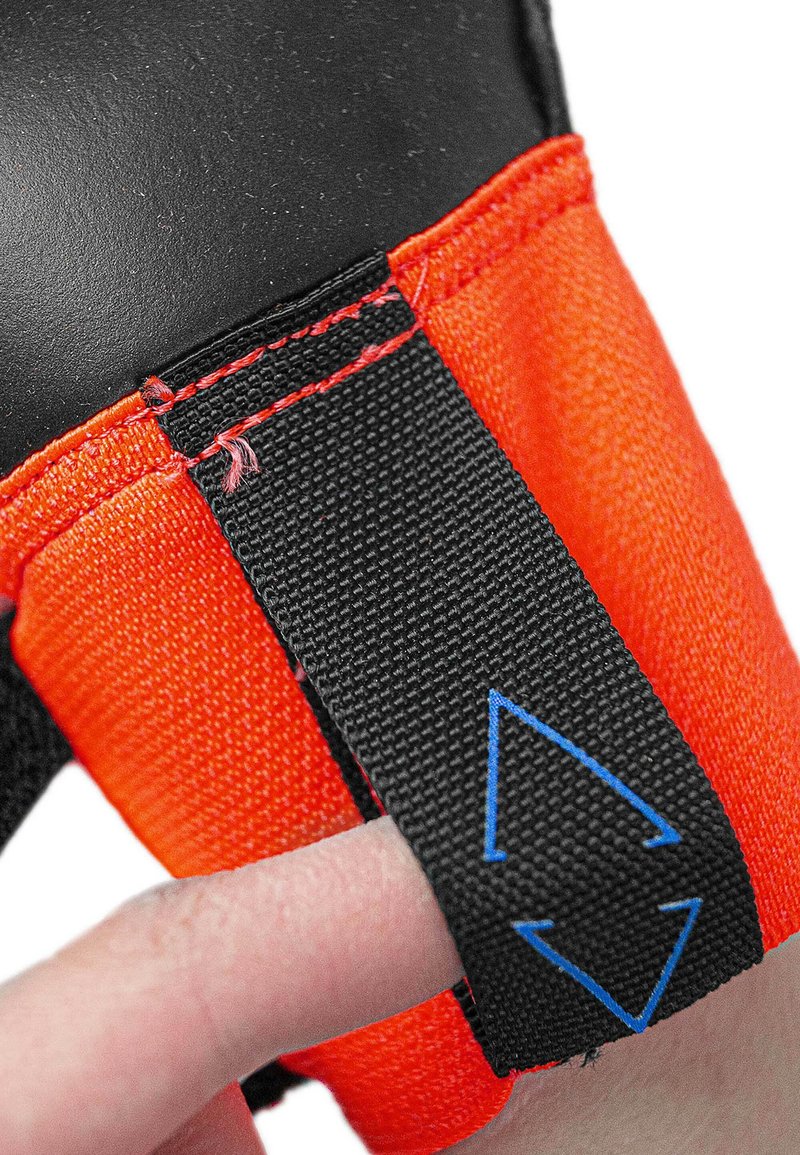 Black and orange glove with textured grip, featuring a black strap with blue arrows for adjustment and red stitching along the seams.