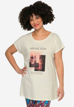 Camiseta de algodón color crema con mangas cortas, que presenta una impresión gráfica de palmeras y un atardecer. El texto dice "BIENVENIDOS A NUESTRO PARQUE DE SUEÑOS".