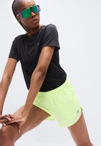 Μαύρο αθλητικό μπλουζάκι συνδυασμένο με neon κίτρινες βερμούδες. Οι βερμούδες διαθέτουν ελαστική μέση με κορδόνι και διακριτική αντανακλαστική σήμανση στην πλευρά.