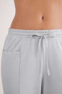 Lichtgrijze joggingbroek met een elastische tailleband, verstelbaar trekkoord en zijzakken. Glad materiaal met een zachte textuur.