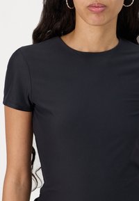 Black fitted short-sleeve top made from a smooth, stretchy fabric. Features a round neckline and a simple, seamless design.