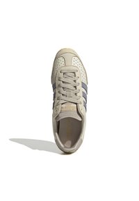Beżowe zamszowe sneakersy z szarymi paskami, perforowanym czubkiem i pasującymi sznurowadłami. Logo wytłoczone na języku z fakturowaną gumową podeszwą.