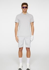 Light gray polo shirt with short sleeves and collar, paired with matching shorts. Accessories include white golf glove and sporty sunglasses.