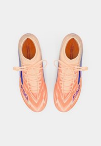 Botas de fútbol de un brillante color melocotón con acentos azules, presentando un diseño texturizado, un prominente logotipo "F50" y cordones tradicionales.