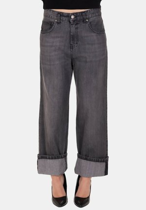 Jeans a vita alta neri sbiaditi con gamba larga e orli risvoltati, indossati con tacchi a punta neri e un top corto nero.