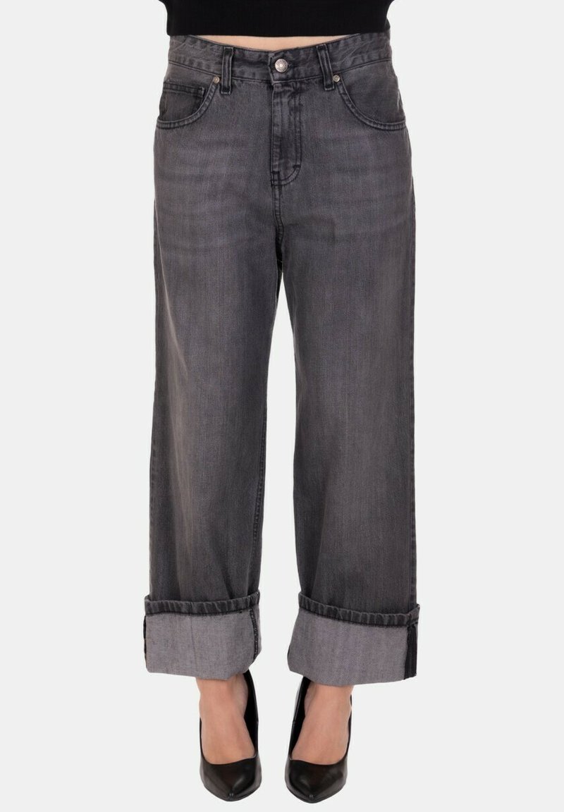 Jeans a vita alta neri sbiaditi con gamba larga e orli risvoltati, indossati con tacchi a punta neri e un top corto nero.