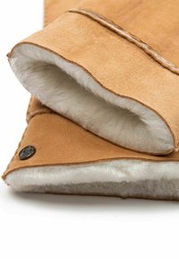 Tan-Suede-Produkt mit weichem weißem Fellfutter, das über eine Nahtdetails und einen Akzent mit dunklem Metallschnappverschluss verfügt. Sechseckige Steppnähte sind sichtbar.