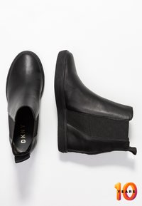 Zwarte leren enkellaarsjes met elastische zijkanten, een ronde neus en rubberen zolen met grip. Voorzien van een trekhaakje voor gemakkelijk aantrekken.