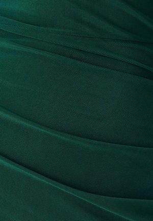 Donkergroene textuurstof met zachte, vloeiende plooien. Het oppervlak heeft een subtiel gaaspatroon, wat diepte en visuele interesse toevoegt.