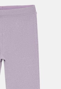 Lilla ribbet strikleggings med en diskret metallisk glans og et elastisk taljebånd, vist fra talje til midt på låret på en hvid baggrund.